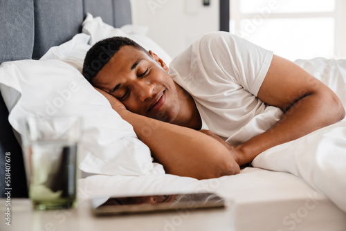 Young african man sleeping in bed at home