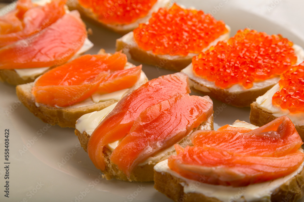 Toasts with red caviar and trout and butter on a plate close-up.