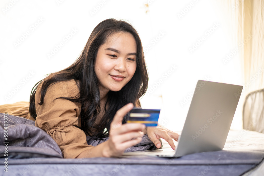 Asian woman using credit card shopping online with computer laptop while vacation travel Asian woman using credit card shopping online with computer laptop while vacation travel