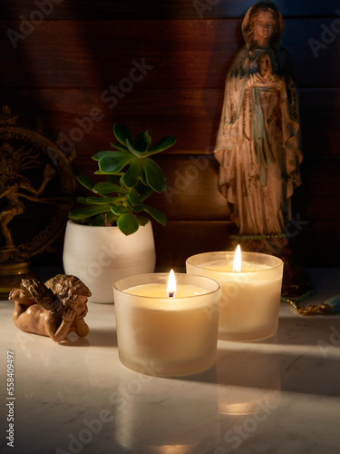 Velas Acesas em Ambiente Tranquilo com Anjinho Olhando e Santa ao Fundo photo