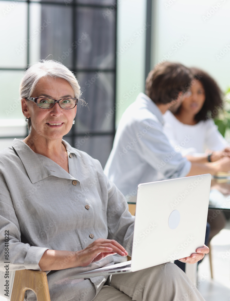 mature woman sitting with laptop looking at camera mature woman sitting with laptop looking at camera