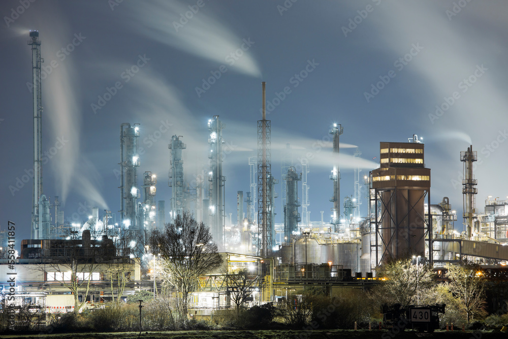 Petrochemical factory by night using gas causing global warming and climate change