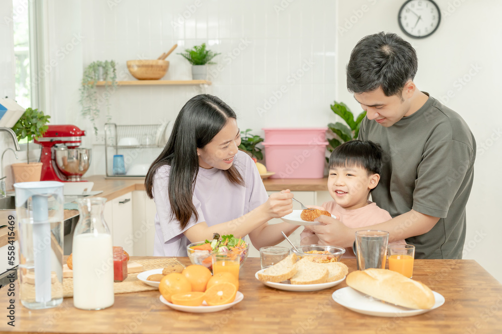 activities together during the holidays. Parents and children are having a meal together during the holidays. boy is teasing his father by giving him bread and vegetables. activities together during the holidays. Parents and children are having a meal together during the holidays. boy is teasing his father by giving him bread and vegetables.