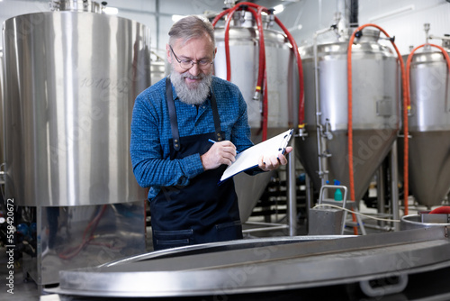 Mature factory worker controlling the brewery process and looking involved