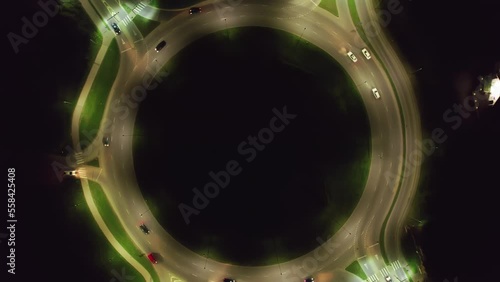 4K aerial top view of a busy roundabout in a city. Aerial footage taken from a drone from a bird's eye view. Drone camera rotates and slowly rises up. Night in the Riga city, Latvia.