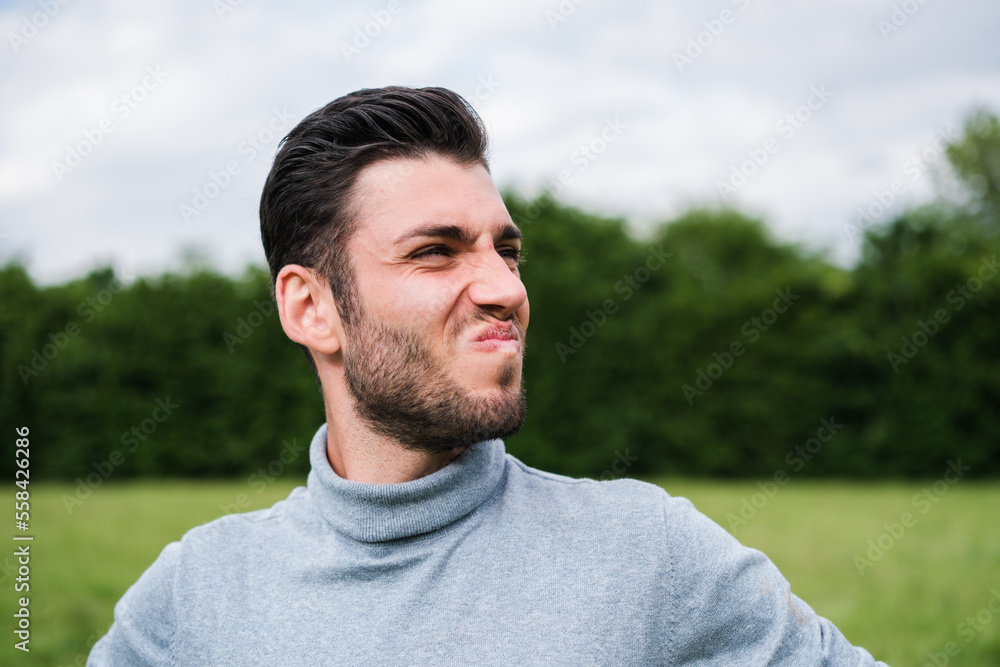 Close-up of a young man outdoors with a face of not being convinced of what they tell him Close-up of a young man outdoors with a face of not being convinced of what they tell him