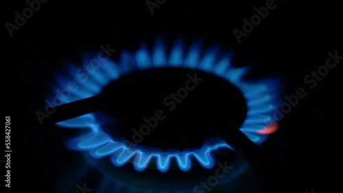 Blue Flame Fire Gas Burner Turning Off in the Dark Close-up. Chef Turns Off Gas Burner Stove in Cooking Kitchen. Switching off the Gas Stove Closeup Macro in the Dark. Switch Off Gas Stove in the Dark photo