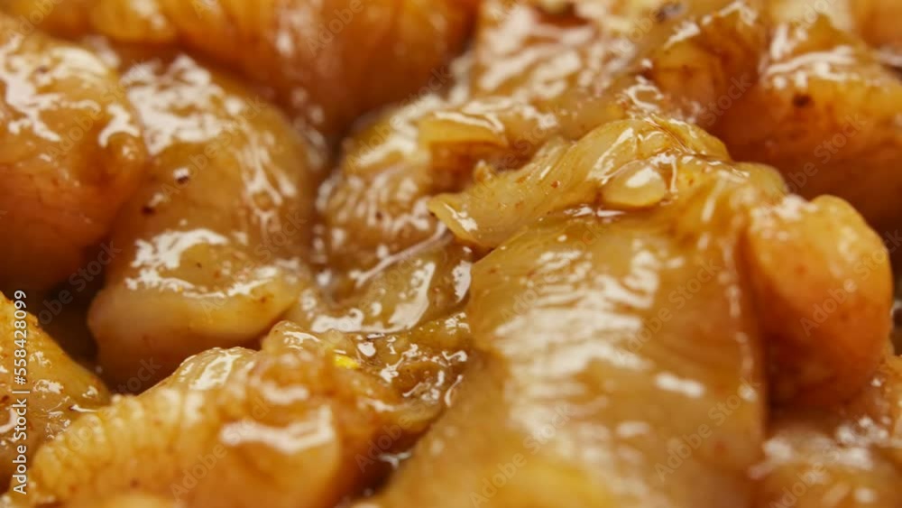 Super close-up of the spoon mixing chicken fillet pieces with spices and sauce Super close-up of the spoon mixing chicken fillet pieces with spices and sauce