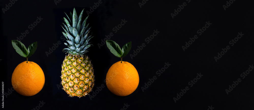 Pineapple and orange on the black background. Copy space. Close-up. Pineapple and orange on the black background. Copy space. Close-up.