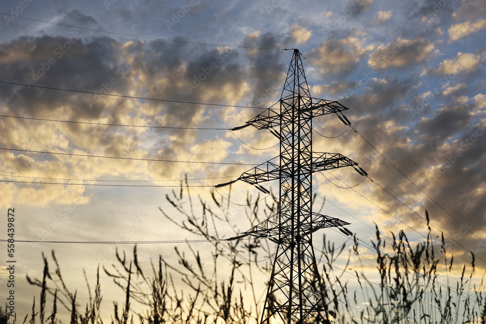Silhouette of high voltage tower with electrical wires and dry grass on ...