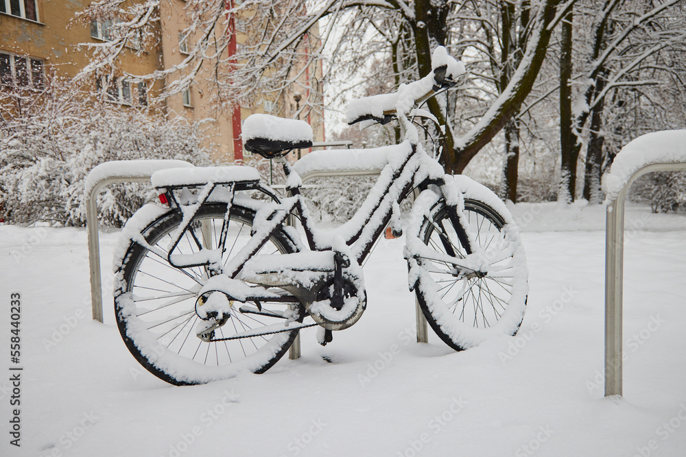 A parked bicycle covered with snow stands on the street. A parked bicycle covered with snow stands on the street.
