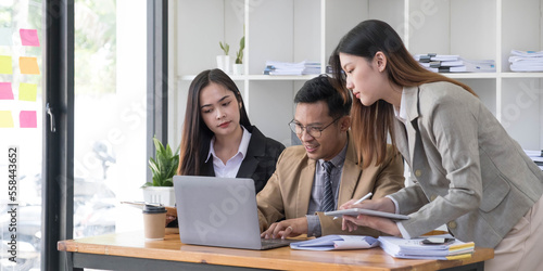 Group of young asian business people in smart casual wear working together in creative office using laptop.