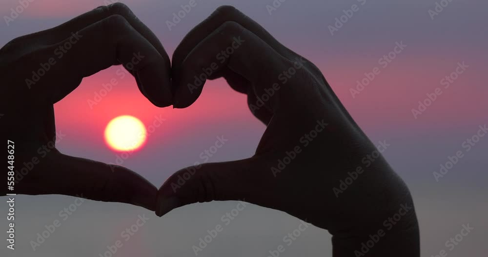 Female hands in the form of heart with the sunlight passing through the hands at sunset on the sea. Hands in shape of love heart. Love concept sea vacation Female hands in the form of heart with the sunlight passing through the hands at sunset on the sea. Hands in shape of love heart. Love concept sea vacation