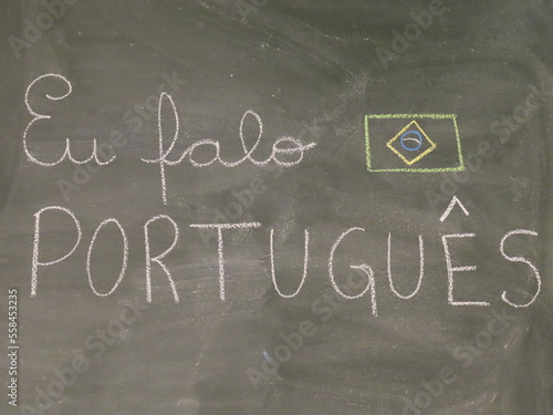 Frase EU FALO PORTUGUÊS escrita com giz de lousa em quadro escolar verde e desenho da bandeira do Brasil  photo