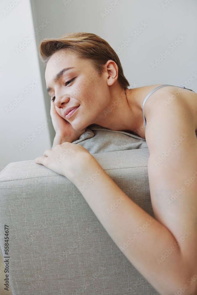 Happy woman smile lying at home on the couch relaxing on a weekend at home with a short haircut hair without filters on a white background, free copy space Happy woman smile lying at home on the couch relaxing on a weekend at home with a short haircut hair without filters on a white background, free copy space