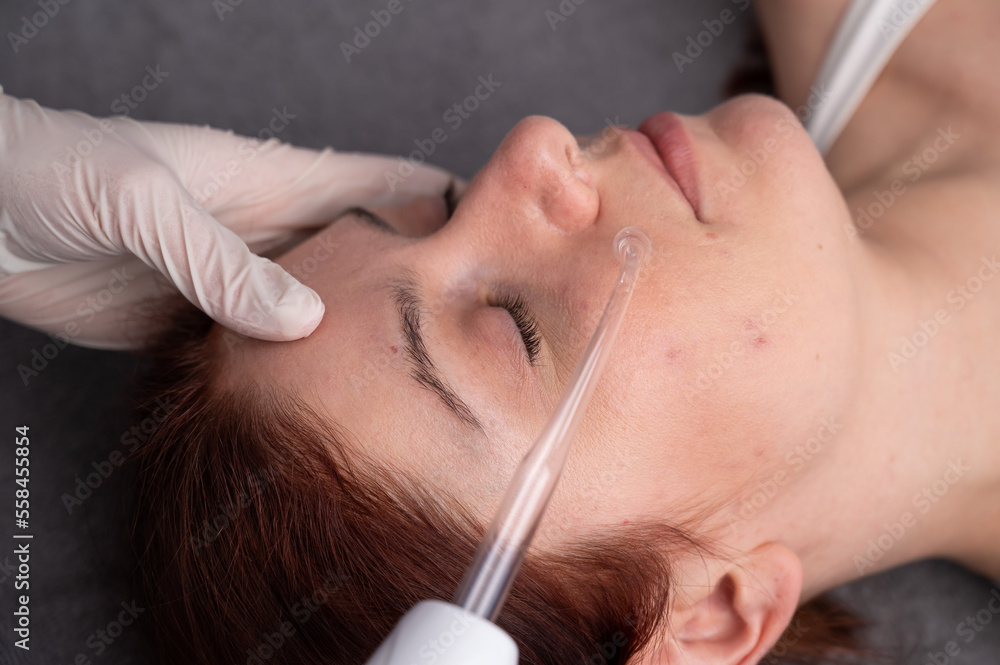 Φωτογραφία The doctor uses the darsonval apparatus against acne on the face of a female patient