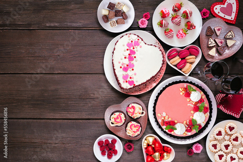 Valentines Day side border of mixed desserts and sweets. Above view over a dark wood background. Love and hearts theme. Copy space.