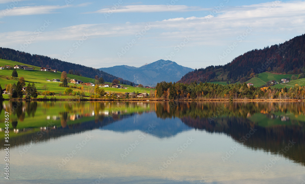 Herbststimmung in der Morgensonne im Kaisergebirge in den österreichischen Alpen mit Blick über den Walchsee mit Hügel und Bergen im Hintergrund