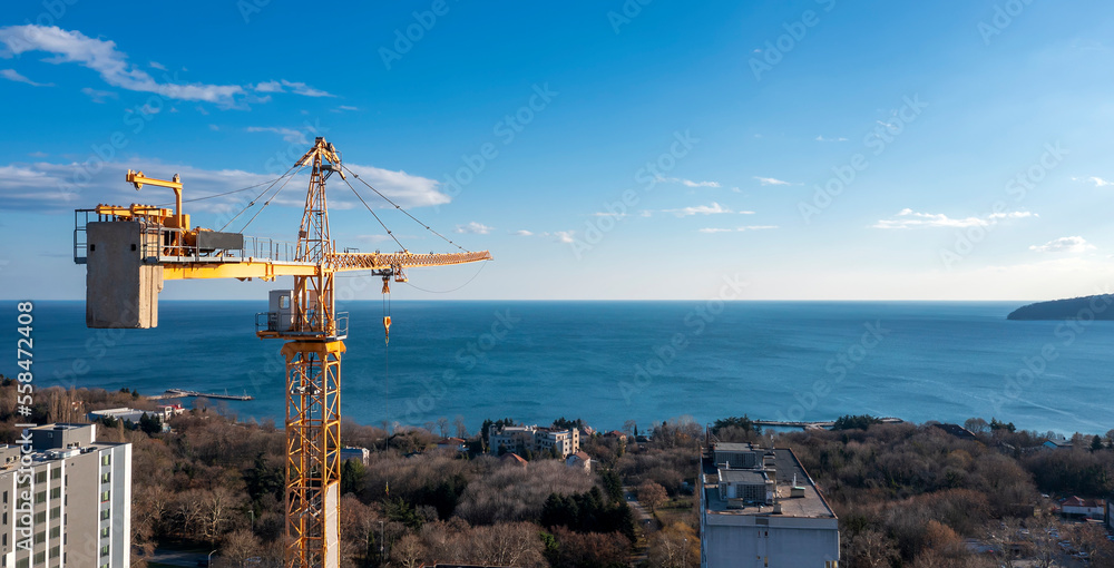 Panoramic view from a drone to construction tower crane against a blue sky