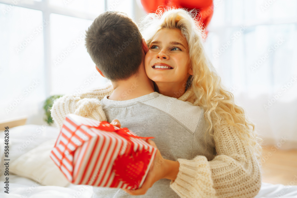 Exchange of gifts. Young couple at home celebrating Valentine's Day. Romantic day together. Exchange of gifts. Young couple at home celebrating Valentine's Day. Romantic day together.