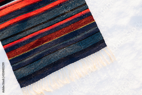 Traditional handwoven Sami fabric, raanu, in the snow. 
Finland