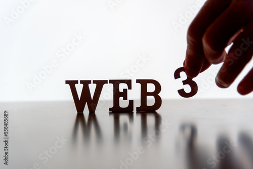 WEB 3 spelled out in letters with hand placing the 3, backlit with white on reflective surface. 