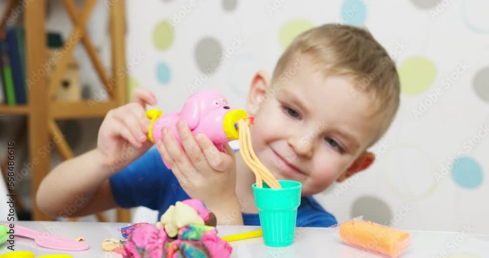 Cute children sitting at the table and plays with playdough Cute children sitting at the table and plays with playdough