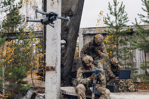 Mobile military base, soldier engineer transmits aerial pictures and data from drone to artillery. Concept of smart war by robots