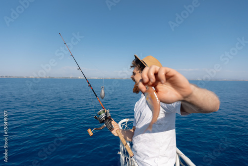 Fisherman is frustrated with catch of small fish for line in blue sea. Sad and disappointed face of man on fishing trip