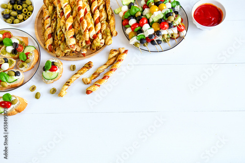 Snacks for the New Year's Eve party and carnival: sausages in puff pastry, puff pastry and pesto sticks, cheese and vegetable skewers, sandwiches and tomato sauce