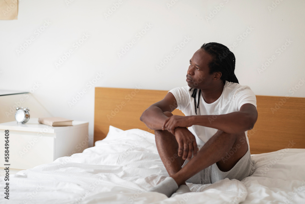 Portrait Of Pensive Young Black Male Sitting On Bed And Looking Away, Portrait Of Pensive Young Black Male Sitting On Bed And Looking Away,