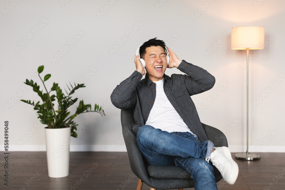 Cheerful emotional mature korean man in wireless headphones with open mouth sings song Cheerful emotional mature korean man in wireless headphones with open mouth sings song