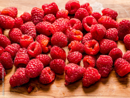 Fresh raw raspberry on wooden board and white isolated background. Fruit product for sale.