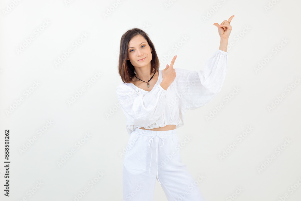 Portrait of young woman standing, raising hands, pointing with index fingers, looking at camera on white background. Portrait of young woman standing, raising hands, pointing with index fingers, looking at camera on white background.