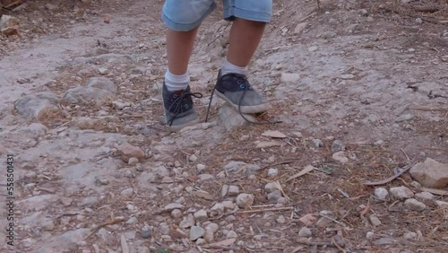 Toddler with untied shoelaces walking on the rocky dusty path in the park. Low angle focus on shoes. High quality FullHD footage photo