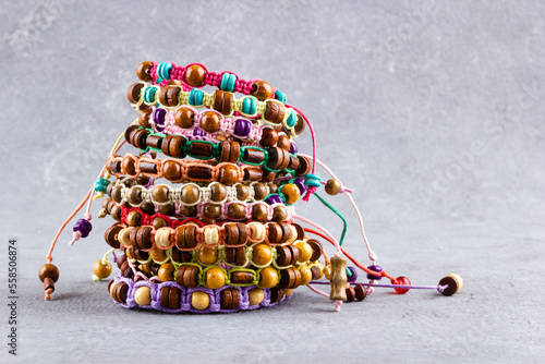 A stack of bracelets made of wooden beads and natural cord on a gray background.