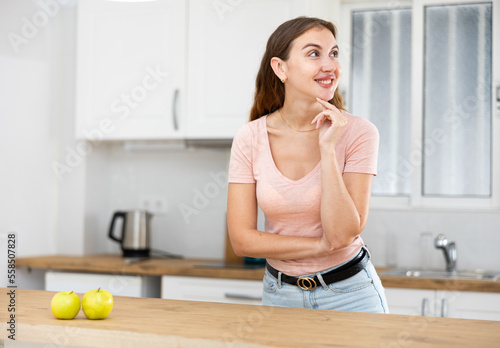 Happy young woman posing near a table in a home kitchen © JackF