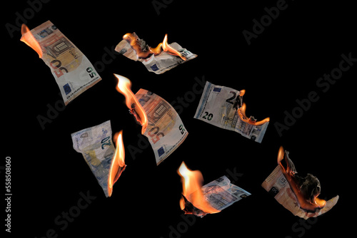 Burning money, twenty and fifty euro banknotes with flames flying isolated against a black background, concept for inflation, finance, investment risk and currency, copy space, selected focus