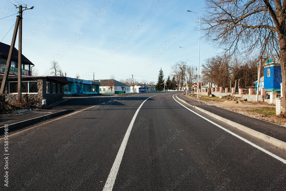 Fototapeta premium New asphalt road with markings and road signs in the sun's rays
