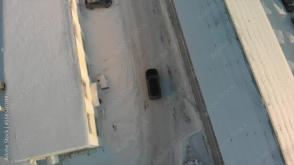 Aerial view of industrial part of the city with driving car. Road and roofs are covered with snow. Black car is driving between industrial buildings. High quality FullHD footage Aerial view of industrial part of the city with driving car. Road and roofs are covered with snow. Black car is driving between industrial buildings. High quality FullHD footage