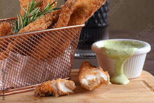 portion of fried fish, fried chicken strips inside metal basket tasty snack