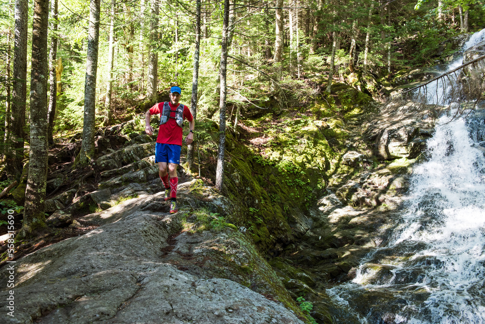 Hiker alongside the Beaver Brook Cascades in Kinsman Notch, New Hampshire Hiker alongside the Beaver Brook Cascades in Kinsman Notch, New Hampshire