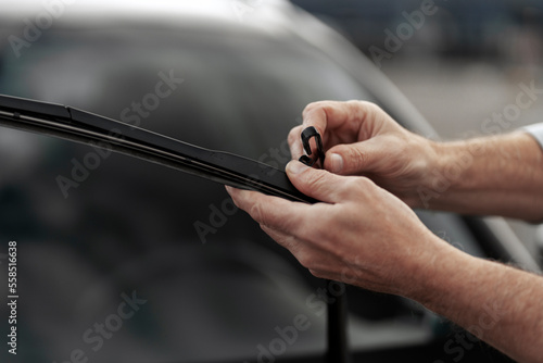 Details on technician's hands changing windshield wipers blades on car. Installation of car wipers