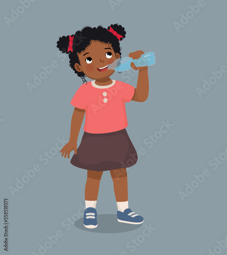 Cute little African girl feeling thirsty drinking fresh water from a bottle