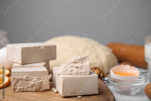 Blocks of compressed yeast and ingredients on wooden table, closeup
