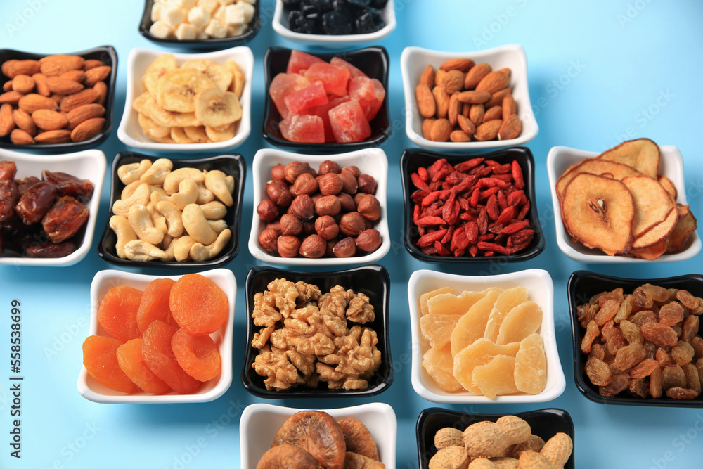 Bowls with dried fruits and nuts on light blue background Bowls with dried fruits and nuts on light blue background