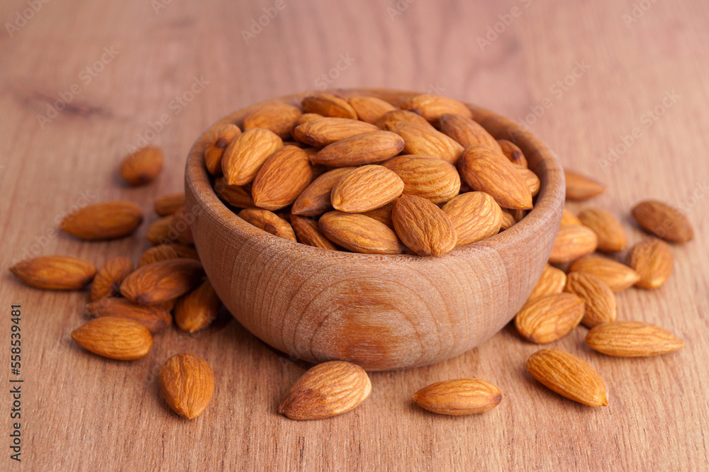 Tasty almonds in bowl on wooden table Tasty almonds in bowl on wooden table