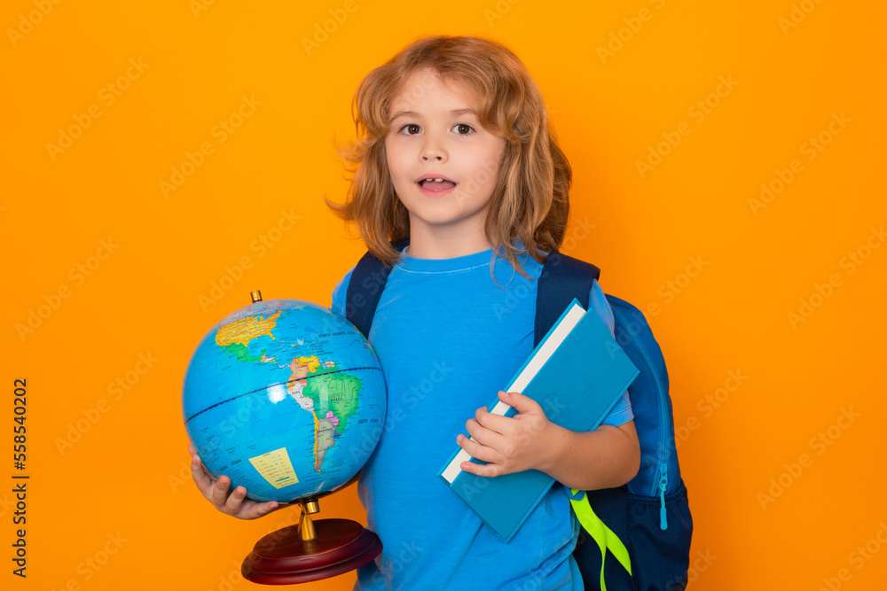 Fototapeta premium Smart child, clever school kid. School boy hold world globe and book, isolated on yellow studio background. School and kids. Cute blonde child with a book learning. Knowledge day.