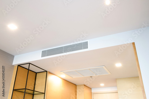 Foto Ceiling mounted cassette type air conditioner and modern lamp light on white ceiling