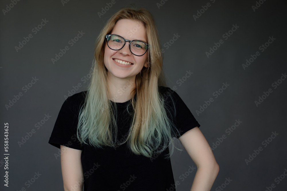 Portrait of young happy good-looking woman student with long fair hair standing on grey background, looking at camera. Portrait of young happy good-looking woman student with long fair hair standing on grey background, looking at camera.
